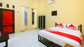 A hotel room with a bed, a wardrobe, a desk, and a door. - Hotel O El Shaday Family Residence (Banyuwangi)