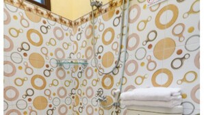 A bathroom with a toilet, a shower, and patterned tiles. - Hotel O El Shaday Family Residence (Banyuwangi)