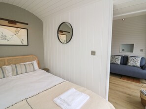 A bedroom with a bed, a bedside table, a mirror, and a wall-mounted TV. - Ceunant (Aberystwyth)