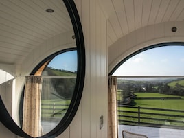 A room with large arched windows offering a view of a green landscape.