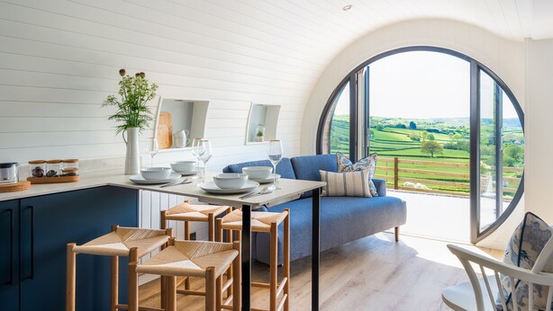 A modern kitchen with a dining area, featuring a large window with a countryside view. - Ceunant (Aberystwyth)