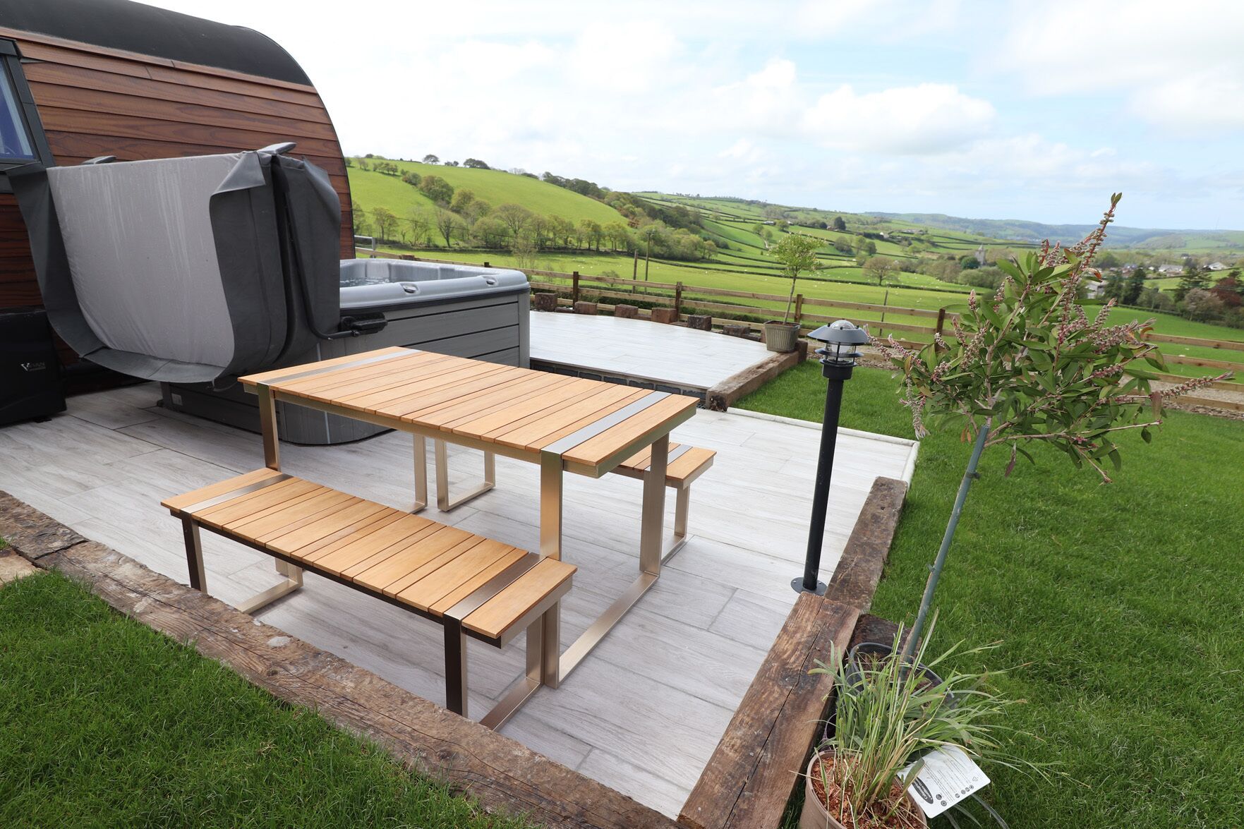 A wooden deck with a barbecue and a table and bench set.