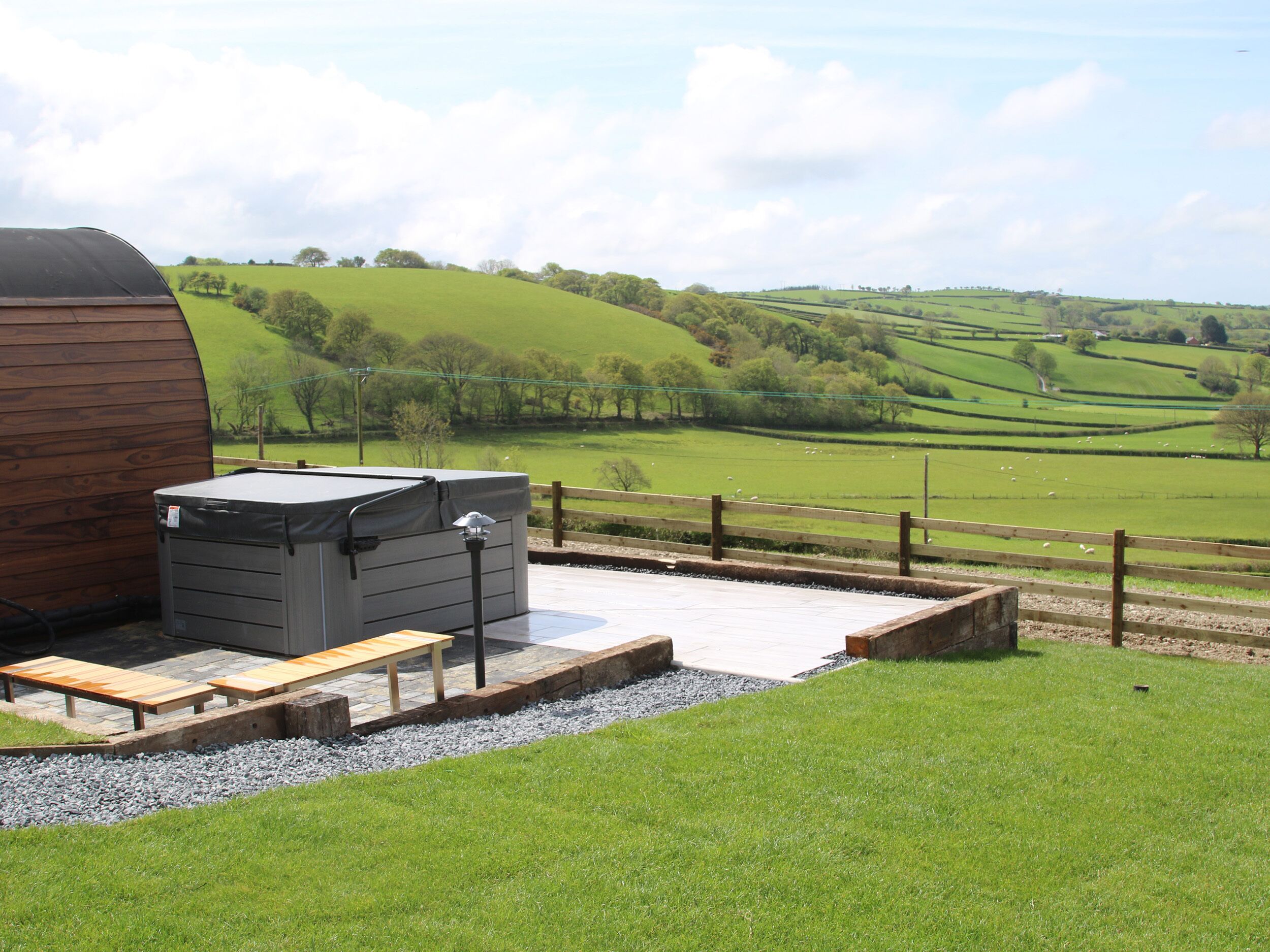 A rustic outdoor area with a wooden shed, a covered storage unit, and a seating area with benches.