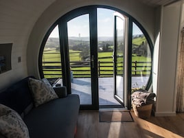 A room with a large arched window, a sofa, and a view of a green landscape.