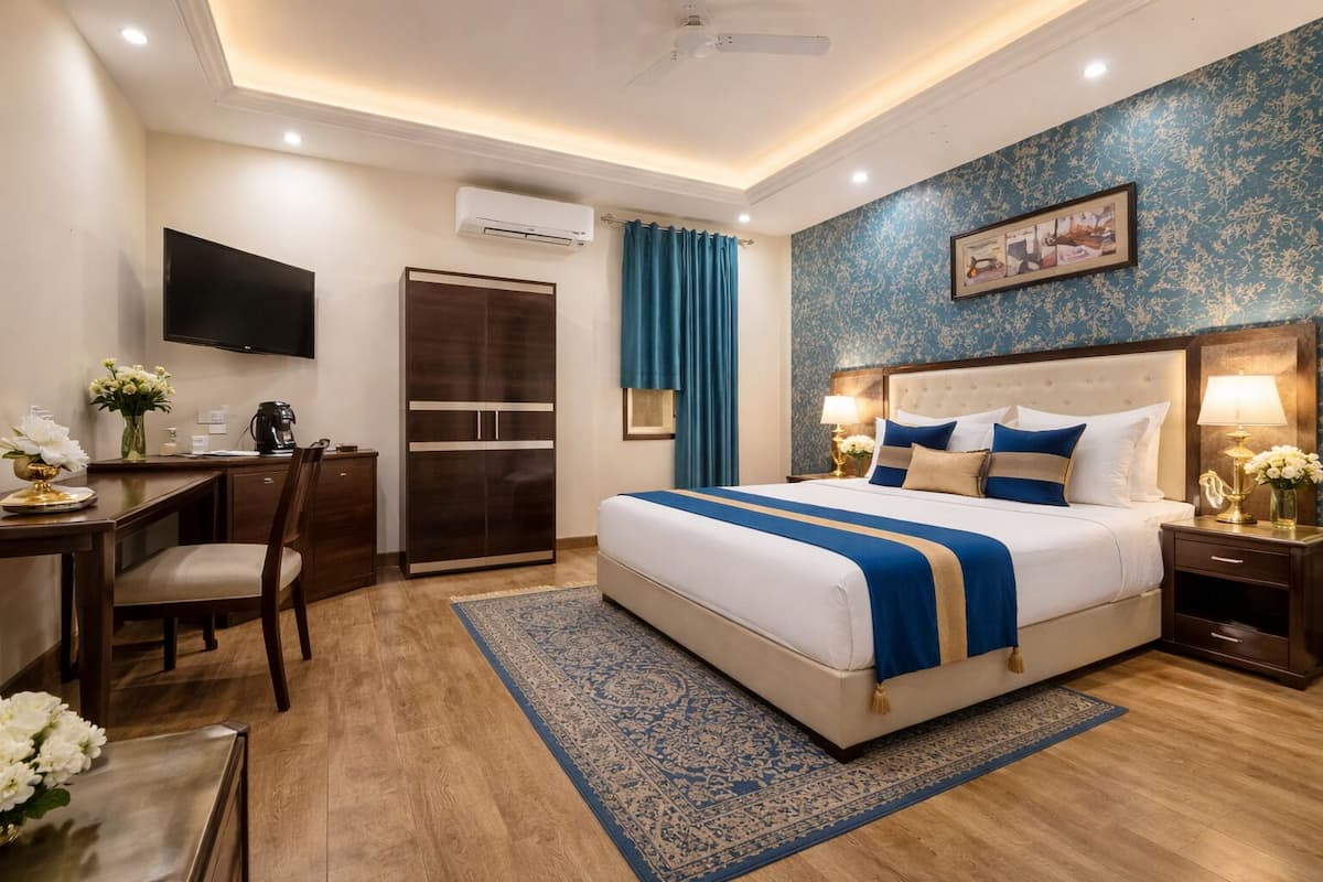 A hotel room with a bed, desk, chair, and a TV.