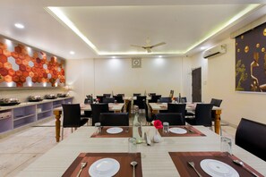 A dining area with tables set for four, chairs, and a decorative wall. - OPO THE ALPINO (New Delhi)