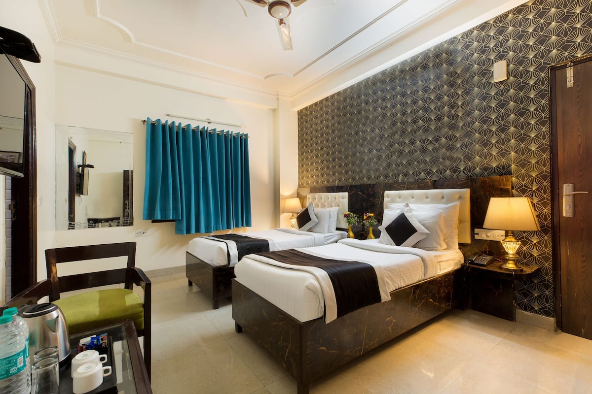 A hotel room with two beds, a mirror, a ceiling fan, and a bathroom with a shower curtain.