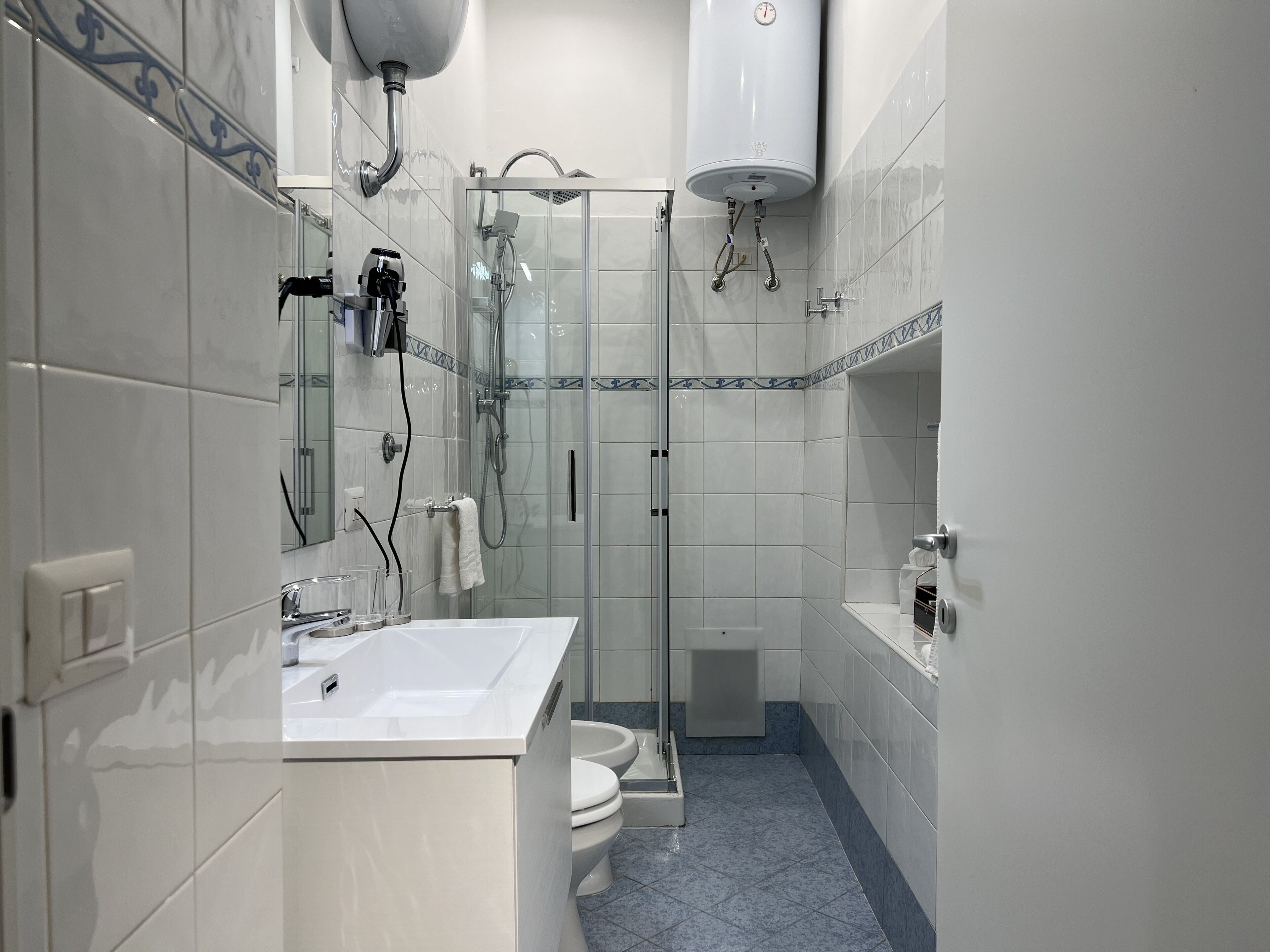 A modern bathroom with a glass-enclosed shower, a white sink, and a toilet.