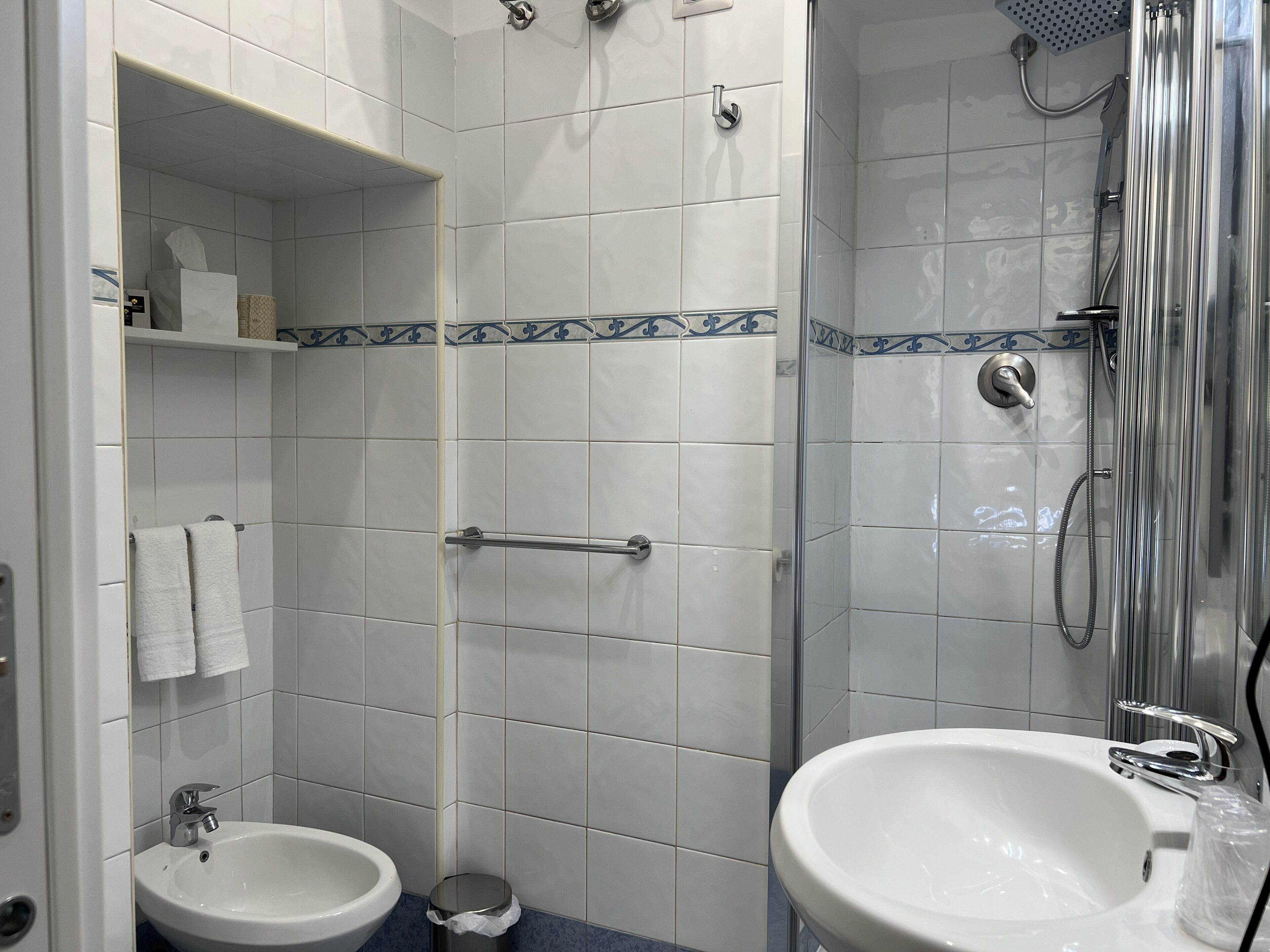 A bathroom with a shower, two sinks, and a toilet.