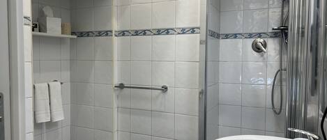 A bathroom with a shower, two sinks, and a toilet.