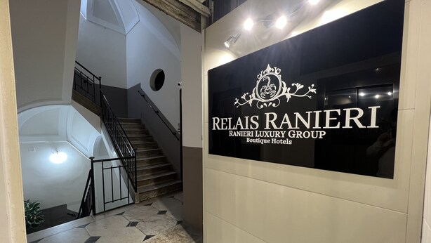 A staircase leading to a room with a sign for Relais Ranieri Boutique Hotels. - Relais Ranieri (Naples)