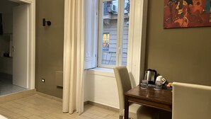 A dining area with a table and chairs, a window with curtains, and a painting on the wall. - Relais Ranieri (Naples)