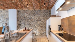 A kitchen with a stone wall, wooden ceiling, and modern appliances. - Spacious Holiday Home in Doische With Private Pool (Doische)
