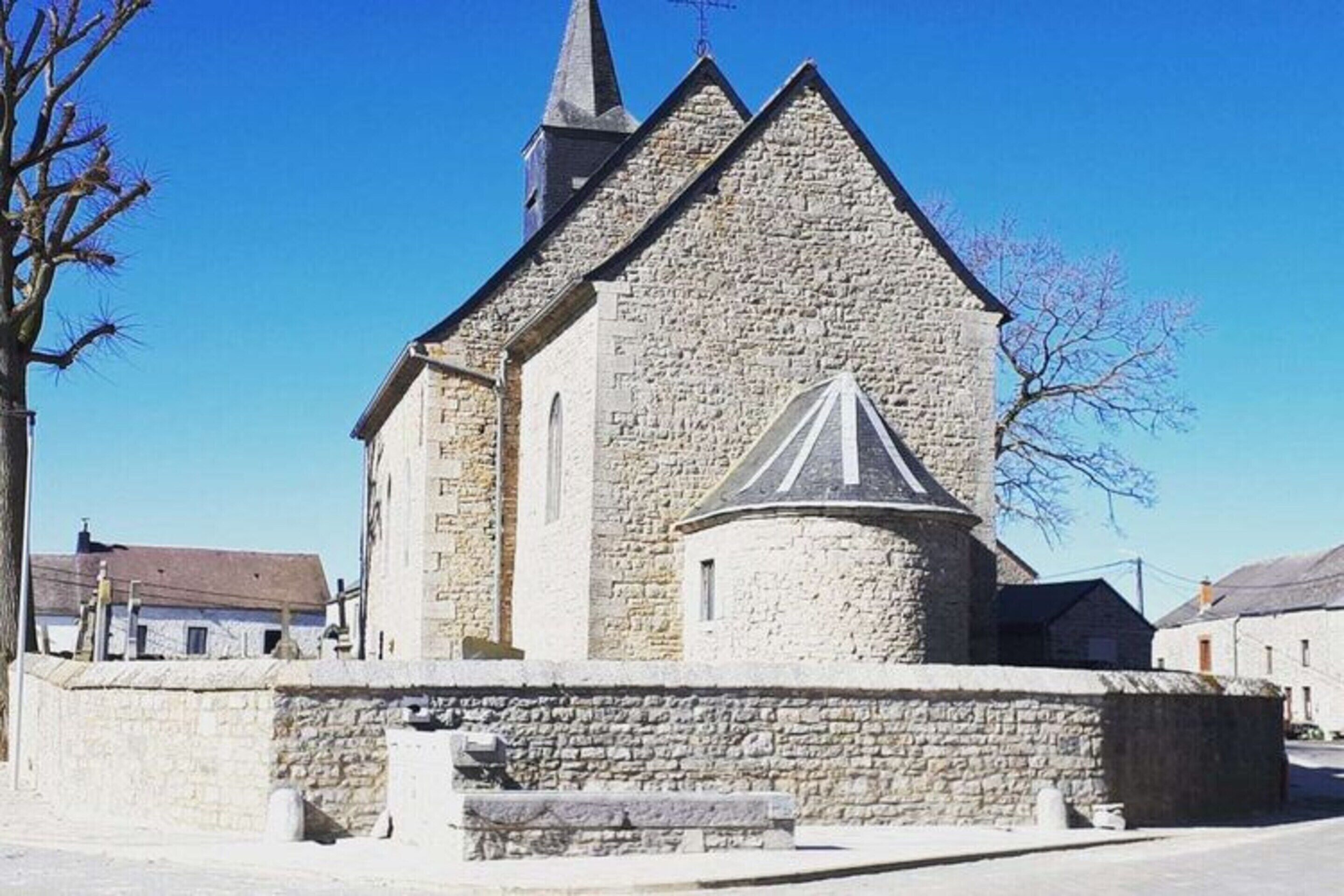 Une église en pierre dotée d’un clocher et d’une petite annexe.