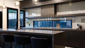 A modern kitchen with a large island, bar stools, a sink, and a view of the outdoors.