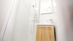 Ein modernes Badezimmer mit Dusche, Holzschrank und Spiegel.