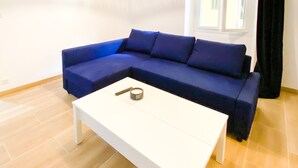 Ein Zimmer mit einem blauen Sofa, einem weißen Couchtisch und einer Pendelleuchte.
