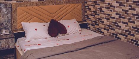 Una cama con cabecera, una mesita de noche y una pared con diseño de ladrillo.