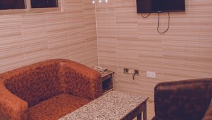 Een woonkamer met een bank, een salontafel en een televisie bevestigd aan een muur met een baksteenmotief.