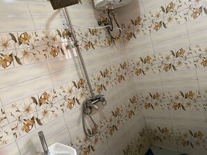 Kylpyhuone, jossa on kukkakuviolliset laatat, suihku ja wc.