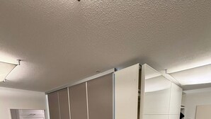 Een kamer met een schuifdeurkast, een keukenhoek met kastjes en een houten vloer.