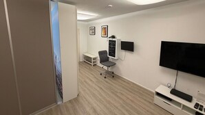 Een moderne kamer met een flatscreen televisie, een bureau en een stoel.