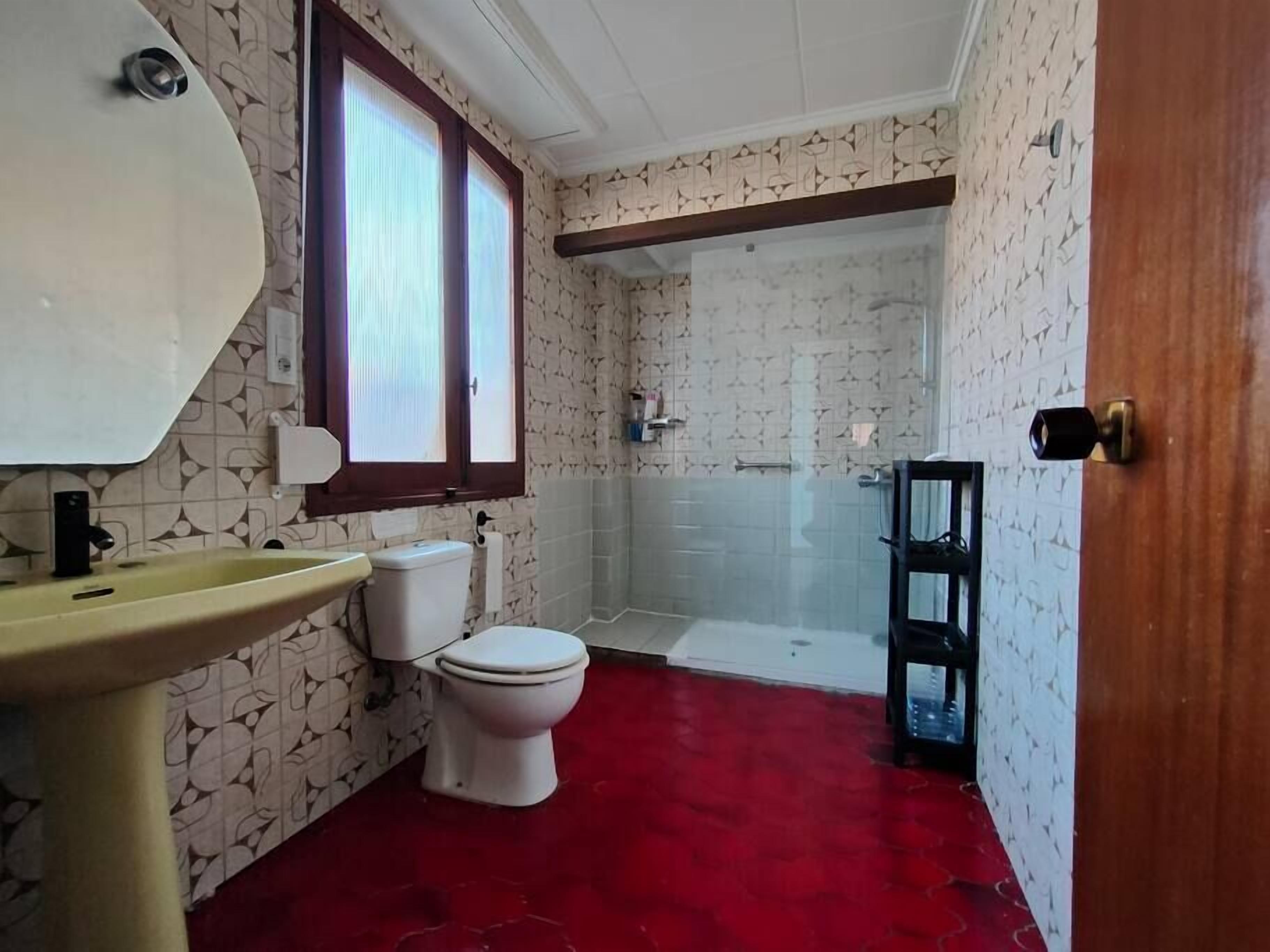 Un baño con inodoro, lavamanos y zona de ducha.