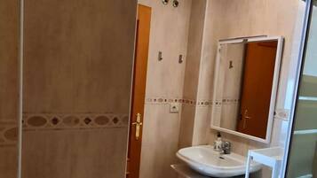 Une salle de bain comprenant des toilettes, un lavabo et un espace douche.