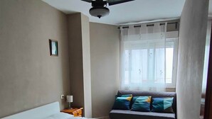 A bedroom with a bed, a ceiling fan, a window with curtains, and a nightstand with a lamp. - Paradis I (with seaviews) (El Grau de Moncofa)