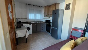 Una cocina funcional con lavadora, refrigerador y microondas.