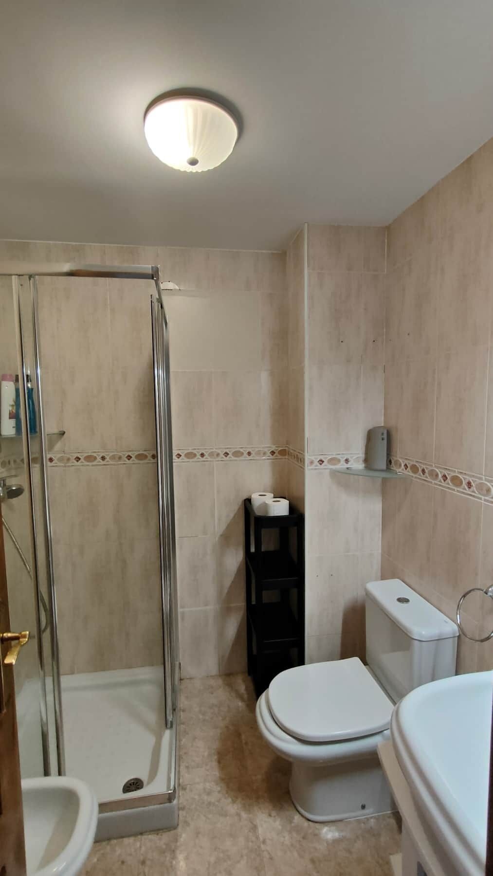 A bathroom with a glass-enclosed shower, a toilet, and a sink.