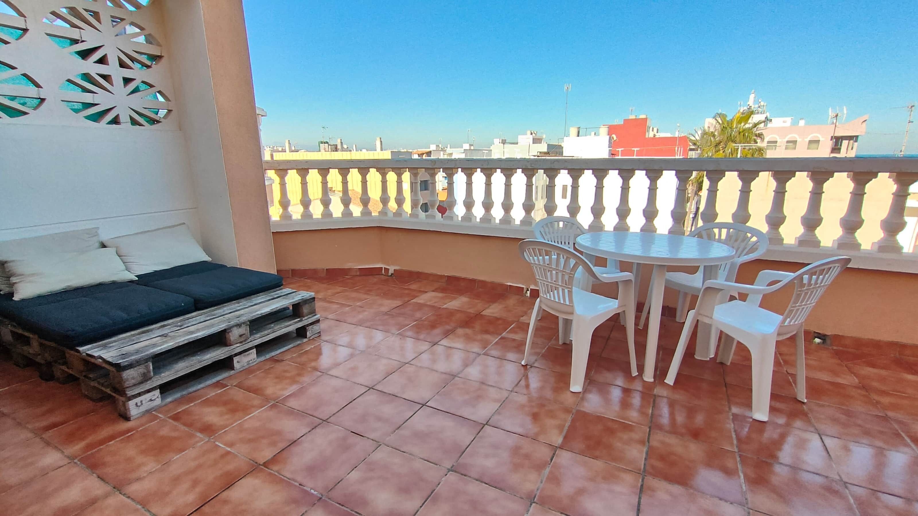 A balcony with a bed, a table, and chairs.
