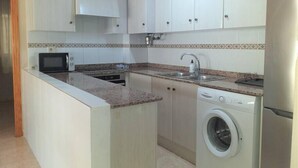 A compact kitchen with white cabinets, a microwave, a sink, and a washing machine. - Paradis II (Seaviews) (El Grau de Moncofa)