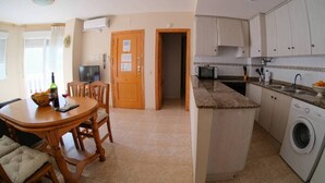 A compact kitchen with a dining area, a washing machine, and a microwave. - Paradis II (Seaviews) (El Grau de Moncofa)
