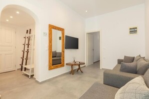 A living room with a sofa, a wooden ladder, a mirror, and a flat-screen TV mounted on the wall. - Mykonos Eight (Mykonos)