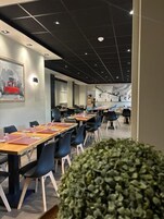 Sala de conferências com mesas compridas, cadeiras e teto com iluminação embutida.