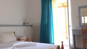 Une chambre d’hôtel avec un lit, une table de chevet, une lampe, une fenêtre avec des rideaux et un miroir.