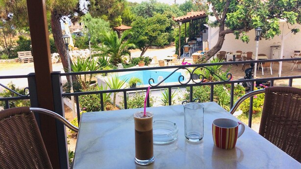 Une terrasse avec une table, des chaises et une vue sur une piscine et un espace verdoyant.