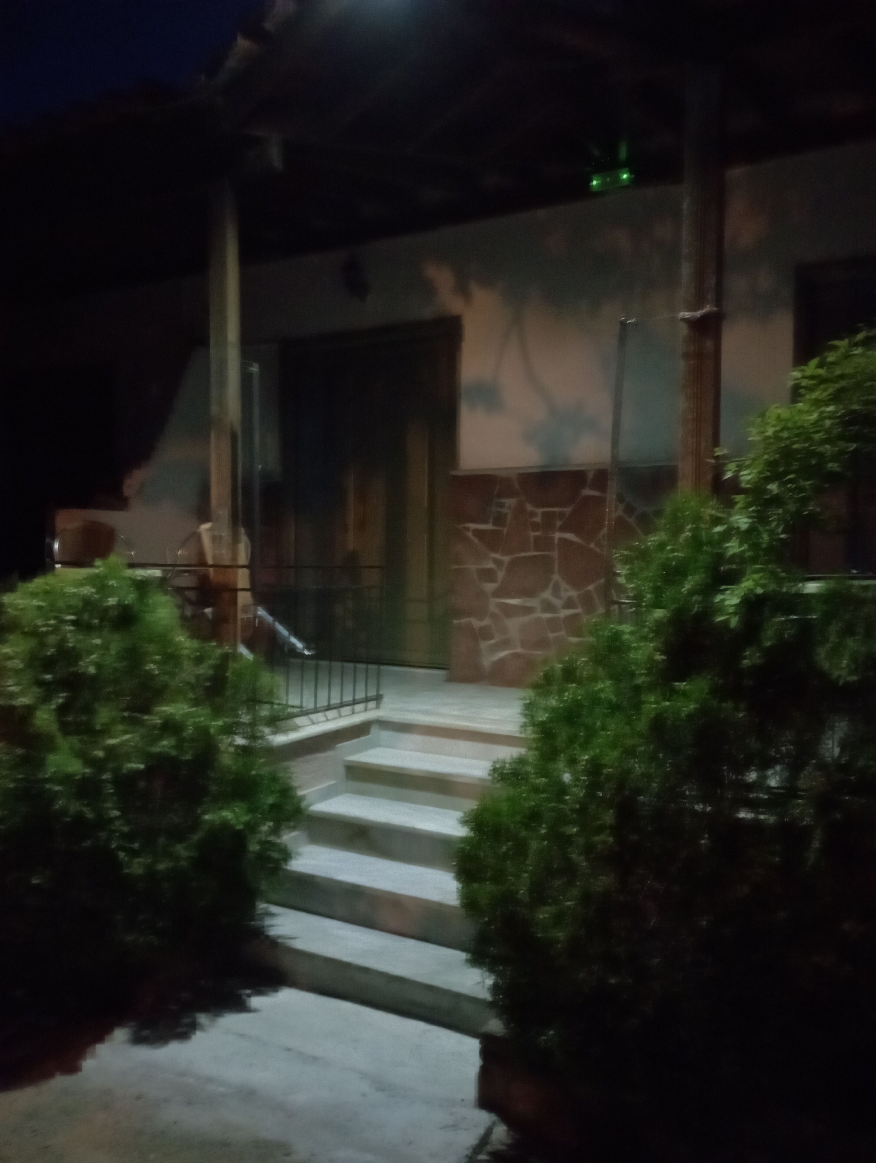Eine Treppe führt zu einem Gebäudeeingang mit Steinmauern und einem Metallgeländer.