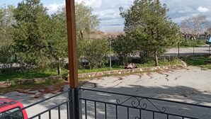 Un balcon fermé offrant une vue sur un parking, des arbres et une côte lointaine.