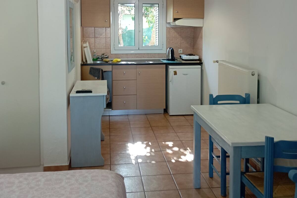 A compact kitchen with a window, a small refrigerator, and a dining area with a table and chairs.