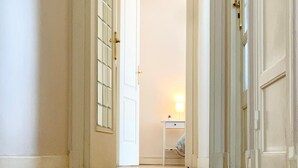 A hallway with wooden flooring, white doors, and a small table with a lamp in the background. - Chic & Spacious Getaway in Nice - 10 min to Beach (Nice)