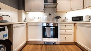 A modern kitchen with white cabinets, a built-in oven, a microwave, and a dishwasher.