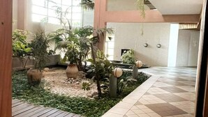 A spacious indoor garden with various potted plants and a tiled floor. - Superbe Appartement Cosy - Plage des Minimes (La Rochelle)