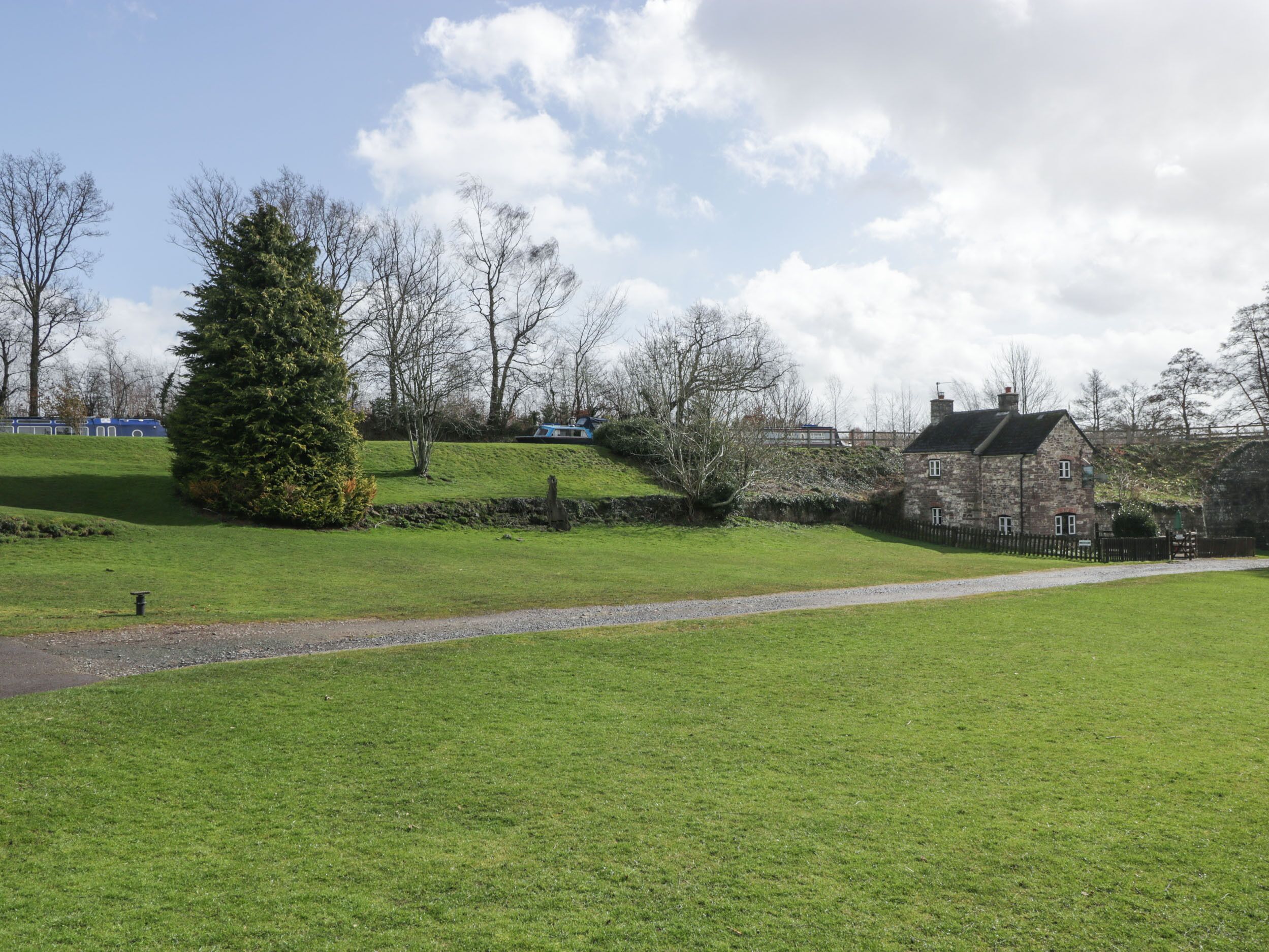 A stone house with a grassy yard and a pathway leading to it.
