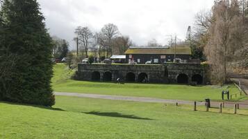 Uma ponte de pedra com várias arcadas, uma área gramada em primeiro plano e um edifício com uma placa que diz 'WATERINGHOUSE'.