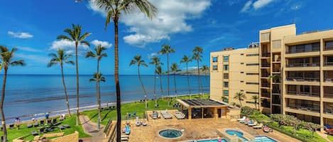 A resort with a swimming pool, palm trees, and a view of the ocean.