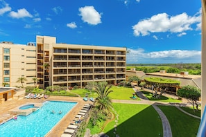 A hotel with a swimming pool, multiple balconies, and a view of the surrounding landscape.