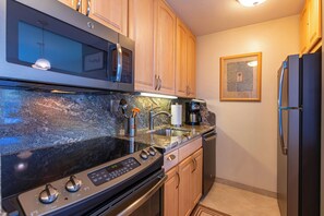 Una cocina con microondas, estufa y lavamanos integrados.