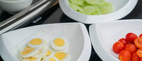 Three white bowls containing sliced boiled eggs, cherry tomatoes, and cucumber slices.